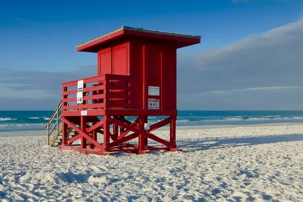 A red lifeguard stand on the white sand of Siesta Key Beach